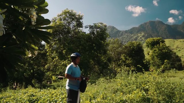 Three people on segway in Pemuteran hills in front of mountains, balinese men and caucasian woman, side view