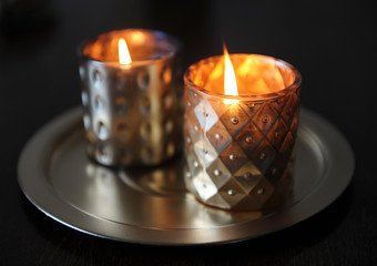 Lighted candles in golden candlesticks on a round gold tray