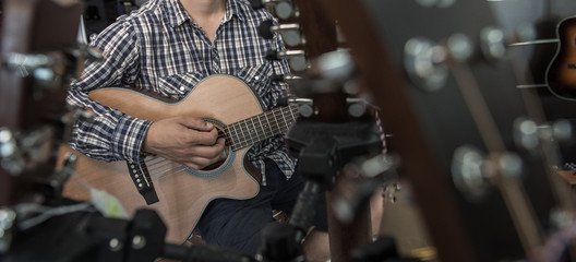 Fototapeta na wymiar Young man playing the guitar in a shop