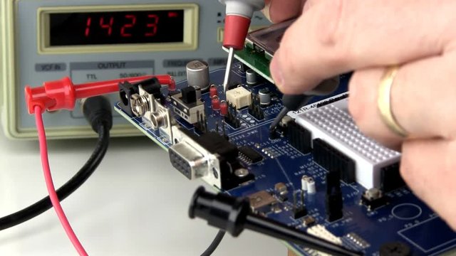 A technician analyzes signals from a development kit circuit board by injecting signal and probing with multimeter
