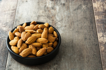 Almonds in black bowl on wooden table

