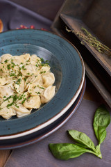 Close up of boiled homemade minced lamb and beef dumpling served in clay blue plate with creamy sauce. Rustic style on wooden background