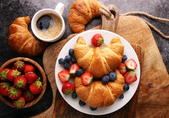 Delicious breakfast with fresh croissants and ripe berries on old marble background
