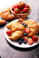 Delicious breakfast with fresh croissants and ripe berries on old marble background