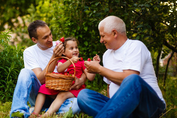 Happy family eating strawberries in the garden