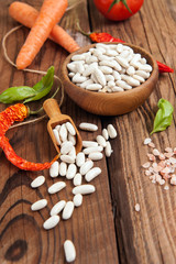 Raw White beans with vegetables on wooden background