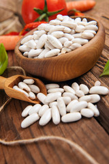 Raw White beans with vegetables on wooden background
