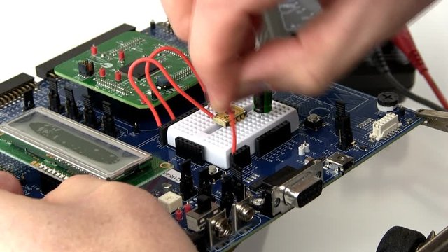 An engineer creates a prototype circuit by wiring components in breadboard area of development board. This clip is time-lapse 