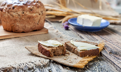 A loaf of bread and pieces of bread and butter on a wooden table