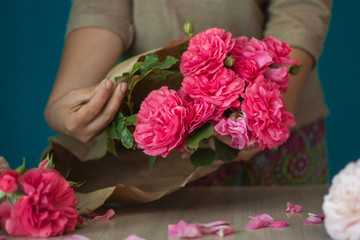 girl florist wraps beautiful pink roses in paper