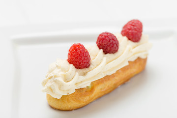 Eclair with vanilla cream and raspberries