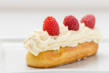 Eclair with vanilla cream and raspberries