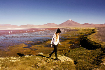 woman near flamingo at Laguna Colorada with volcano behind lake
