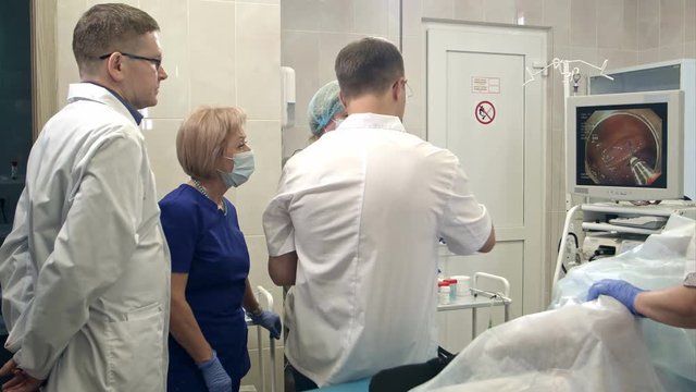 Doctors looking at endoscope monitor during surgical operation