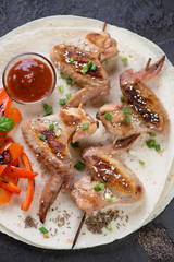 Above view of tortillas with bbq chicken wings skewers, vertical shot