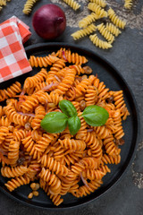 Above view of fusilli pasta cooked with red onion sauce, raisins and pine nuts