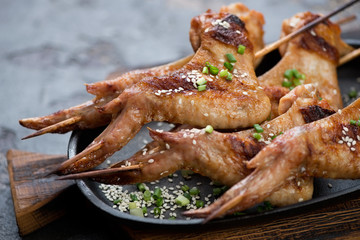 Close-up of barbecued chicken wings on wooden skewers, selective focus, shallow depth of field