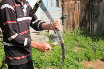 Man sharpening a scythe before mowing