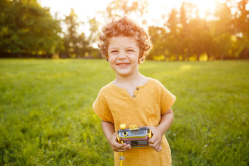 Smiling kid in orange shirt holding camera