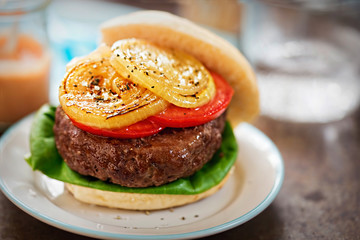 Steak burger with green lettuce, slices of tomatoes and grilled onions - sweet chilli dip