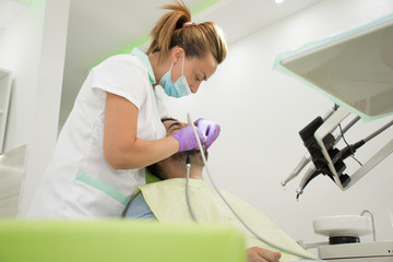 Female dentists examining and working on male patient.Dentist's office.