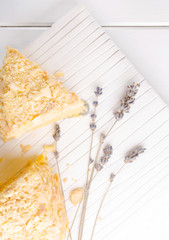 A piece of Napoleon cake on a white wooden background, vertical, selective focus