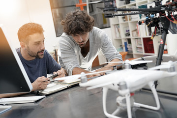 Engineer and technician working together on drone in office