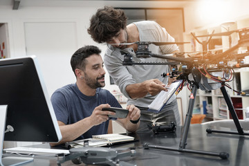 Engineer and technician working together on drone in office - obrazy, fototapety, plakaty