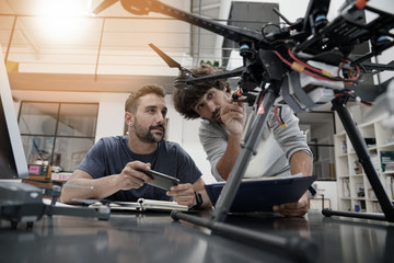 Engineer and technician working together on drone in office - 163392433