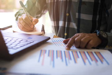 man sitting at the table, analyzes performance and looking at spreadsheet in office. Front view. Coworking. Point to the paper.