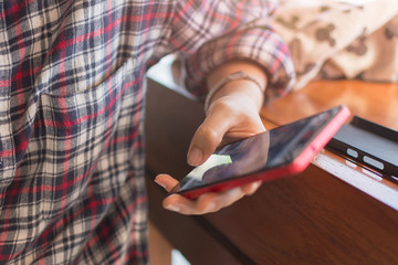 Close up of a young woman's hand typing text message on her smartphone. thai young woman is typing on touch screen mobile phone. Close up of female hand texting a message phone indoor.