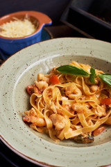 Seafood pasta. Tagliatelle with prawns and spices in tomato-cream sauce. Glass of white wine.