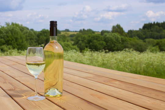 A Bottle Of White Wine With A Glass Arranged In Nature. Picnic Concept