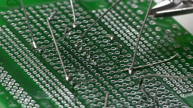 An electrical engineer builds a circuit design by cutting and trimming excess lead length after soldering through hole components to a breadboard by hand