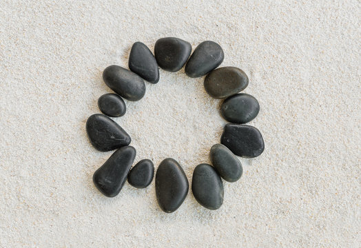 black stones forming a circle on white sand background