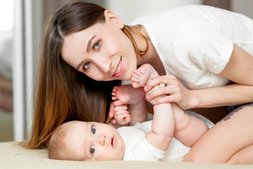 Mom plays with the baby 6 months on the bed at home