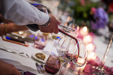 Sommelier pouring wine into glass from mixing bowl, luxury diner