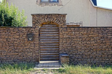 Серый каменный забор и деревянная дверь с почтовый...