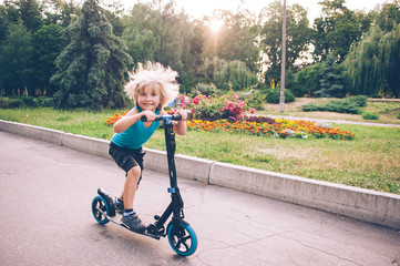 A little boy is riding a scooter in the park © Rakursstudio