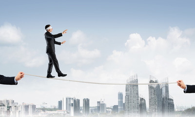Business concept of risk support and assistance with man balancing on rope