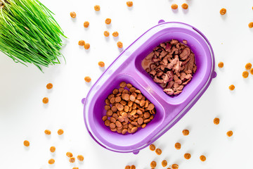 Animal feed in bowl and grass on white background top view
