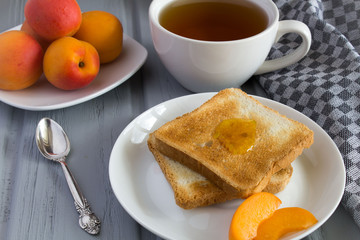 Bread toast with apricot jam,tea and apricots on the grey wooden  background