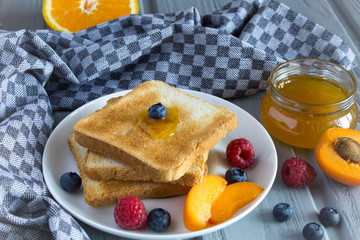 Bread toast with apricot jam and fruit on the grey wooden background