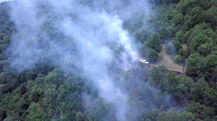 Fototapeta na wymiar smoke of bush fire near village houses in macedonia