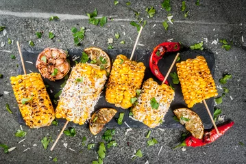 Papier Peint photo Grill / Barbecue Summer food. Ideas for barbecue and grill parties. Grilled corn grilled on fire. With a sprinkle of cheese (mexican elotes), hot chili pepper and lemon. On a dark stone table. Copy space top view