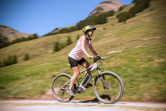 Frau beschleunigt E-Mountainbike in den Alpen
