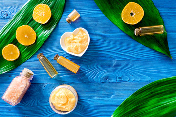 Fototapeta na wymiar Aroma spa set. Citrus scrub, salt and oil on blue wooden background top view copyspace