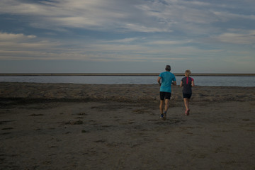 tow people run on the beach in the summer evening