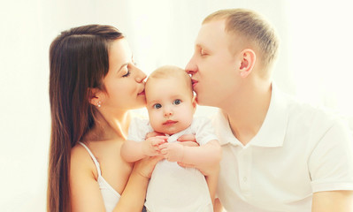 Portrait closeup happy family, mother and father kissing baby