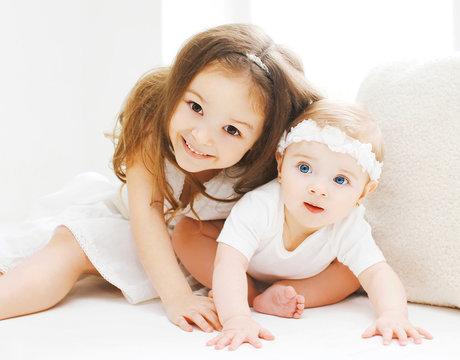 Little sisters together, children playing in white room at home